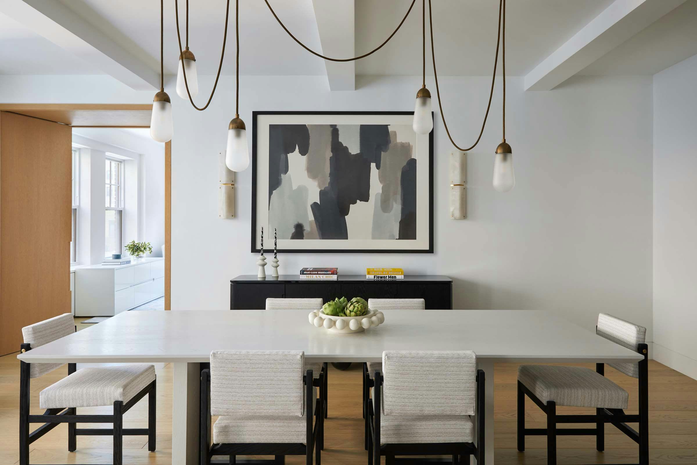 Dining room with white table and balck and white chairs and dangling light fixture